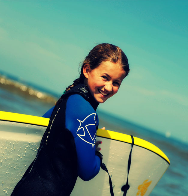 Vrolijk kind in wetsuit met bodyboard op het strand van Scheveningen bij Solbeach.