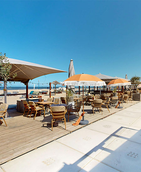 Terras met parasols en houten banken op het strand van Scheveningen bij Solbeach.