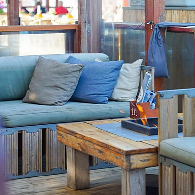 Comfortabele loungehoek met blauwe kussens op het terras van Solbeach Scheveningen.