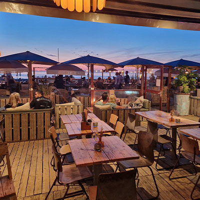 Gezellig verlicht terras bij zonsondergang voor een bedrijfsuitje bij beachclub Solbeach.