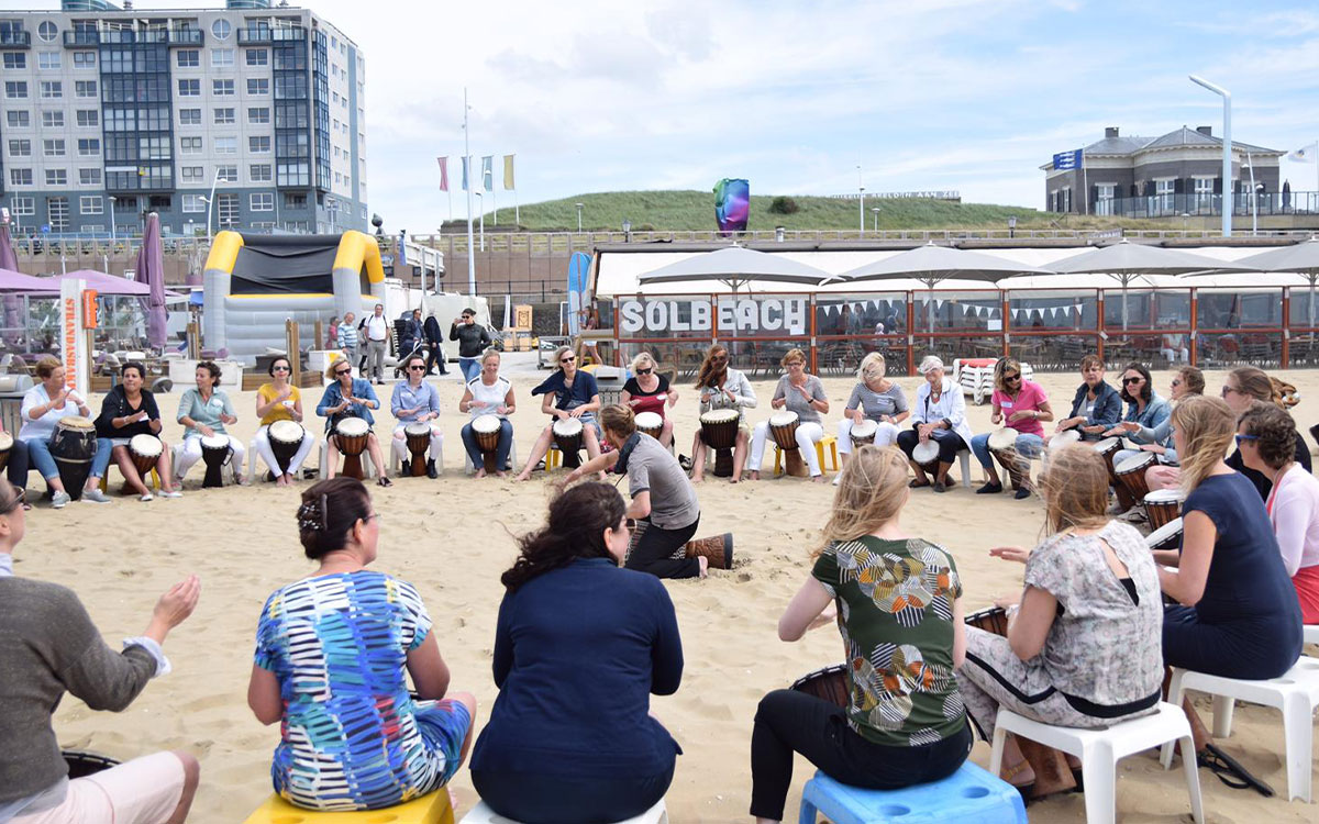 Muzikale teambuilding met een djembé en percussieworkshop op het strand van Scheveningen.