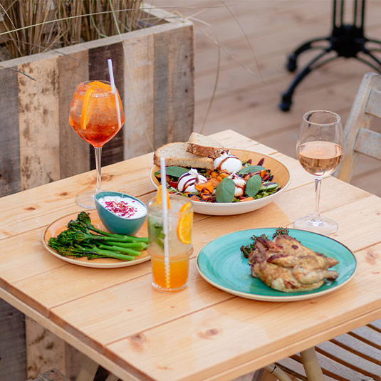 dinersolbeach Zomers diner met cocktails en lichte gerechten op het terras van Solbeach bij zonsondergang.