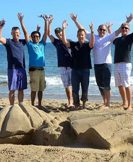 Enthousiaste collega's vieren een geslaagd bedrijfsuitje op het strand bij beachclub Solbeach.