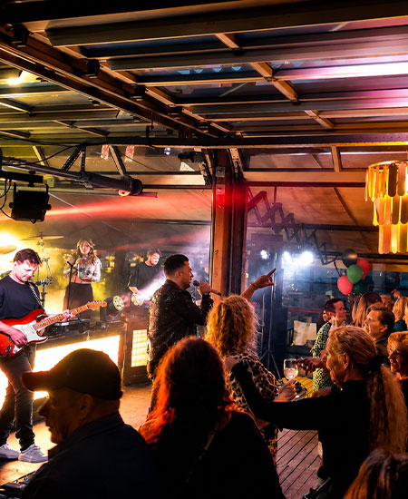 Dansende feestgangers en live entertainment tijdens een personeelsfeest bij beachclub Solbeach.