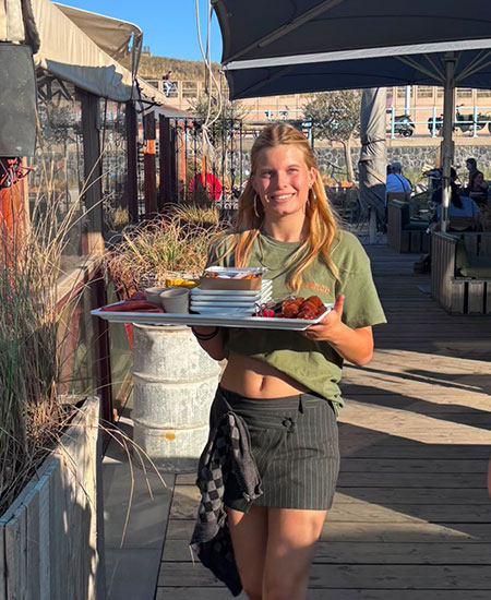 Serveerster brengt drankjes rond op het terras van Solbeach Scheveningen.