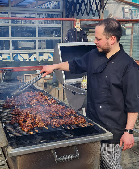 Kok aan het werk bij de grote buitenbarbecue van strandtent Solbeach Scheveningen.
