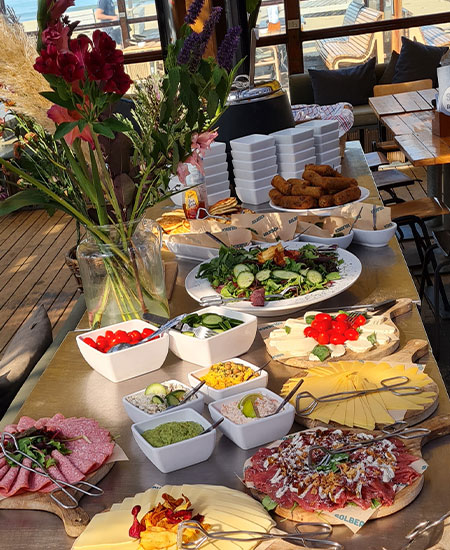 Sfeervol gedekte tafel met verse bloemen en lunch voor een vergadering bij beachclub Solbeach.