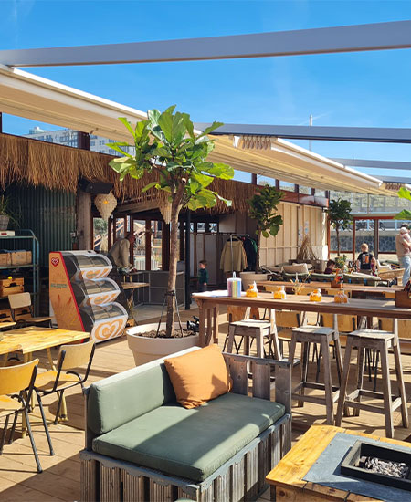 Sfeervol terras met biertafels ingericht voor een personeelsfeest of groepsfeest bij strandtent Solbeach Scheveningen.