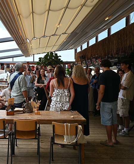 Gasten op het overdekte terras tijdens een feestelijk bedrijfsuitje of verjaardagsborrel bij beachclub Solbeach Scheveningen.