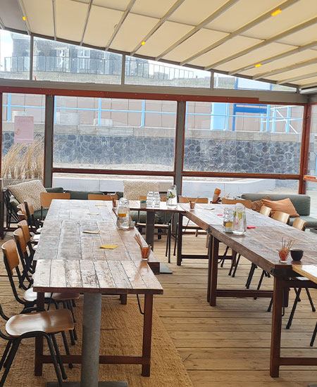 Lange tafels gereed voor een zakelijk diner of vergadering bij strandtent Solbeach.