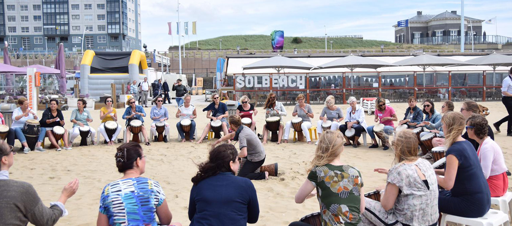 headersolbeachmuzikaal Muzikale djembé workshop op het strand met beachclub Solbeach op de achtergrond.