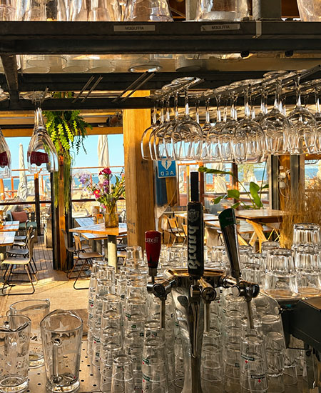 De bar van beachclub Solbeach Scheveningen met rijen wijnglazen klaar voor een evenement.