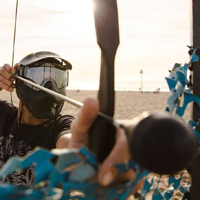 Archery tag beschermmasker en handboog klaar voor actie op het strand van Scheveningen.