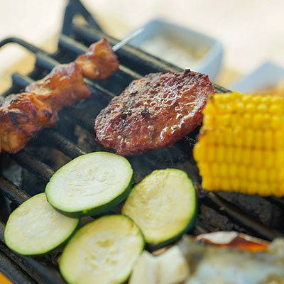 Vlees en groenten op het barbecuerooster tijdens een teambuilding BBQ bij strandtent Solbeach.