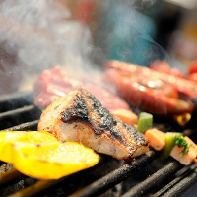 Grillgerechten sissen op de barbecue op het terras van strandtent Solbeach Scheveningen.