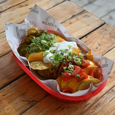 Rijkelijk belegde loaded fries geserveerd op het terras van beachclub Solbeach Scheveningen.