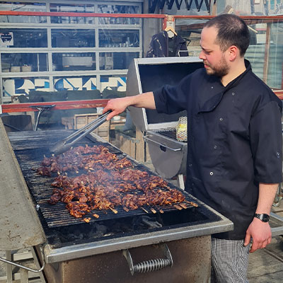 Chef-kok bereidt vlees op de grote barbecue voor een zakelijk bedrijfsuitje bij beachclub Solbeach.