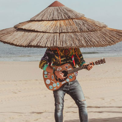 Gitarist met rieten hoed verzorgt live strandmuziek bij beachclub Solbeach Scheveningen.