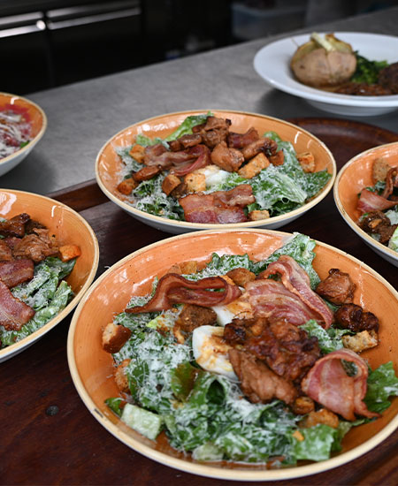 Diverse verse salades en lunchborden geserveerd voor een groep bij strandtent Solbeach.