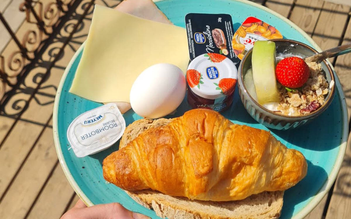 Uitgebreid ontbijtbord met croissant, gekookt ei en vers fruit bij beachclub Solbeach Scheveningen.