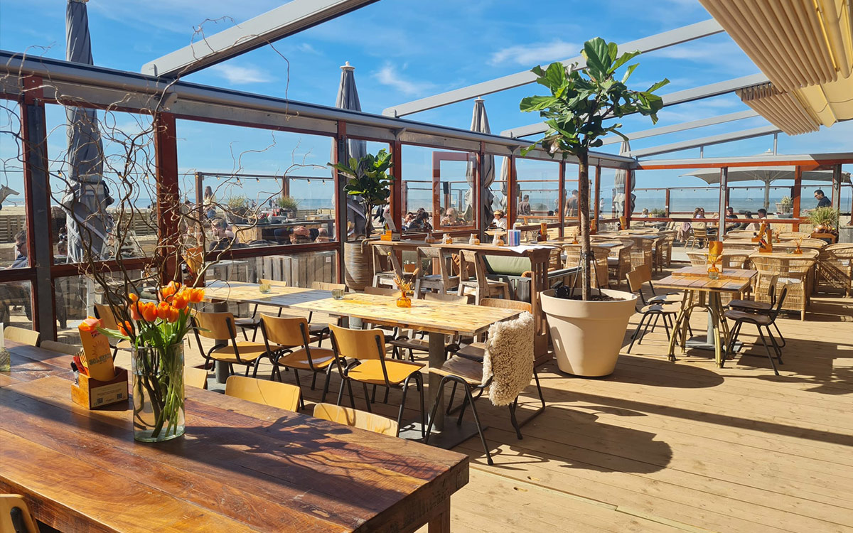 Overzicht van het bruisende strandterras van beachclub Solbeach op een zonnige zomerdag.