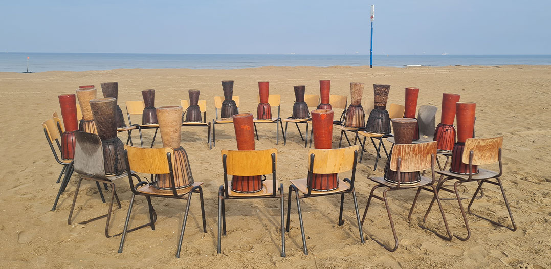 Djembé trommels opgesteld in een kring op het strand voor een muzikaal bedrijfsuitje bij Solbeach.