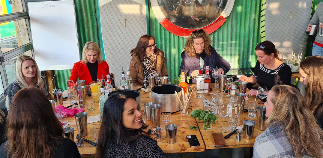 Vriendengroep proost aan tafel tijdens een vrijgezellenfeest bij beachclub Solbeach Scheveningen.